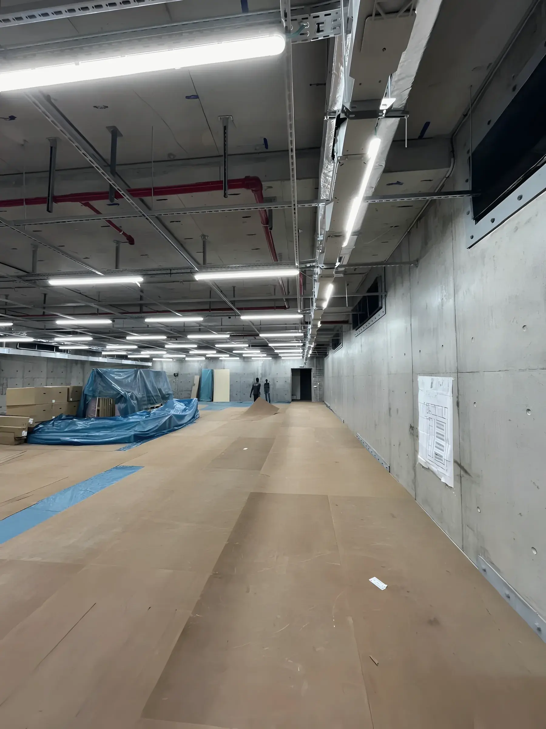 A data hall during fit-out: raised floor pedestals, overhead containment and lighting in place, racks not yet installed