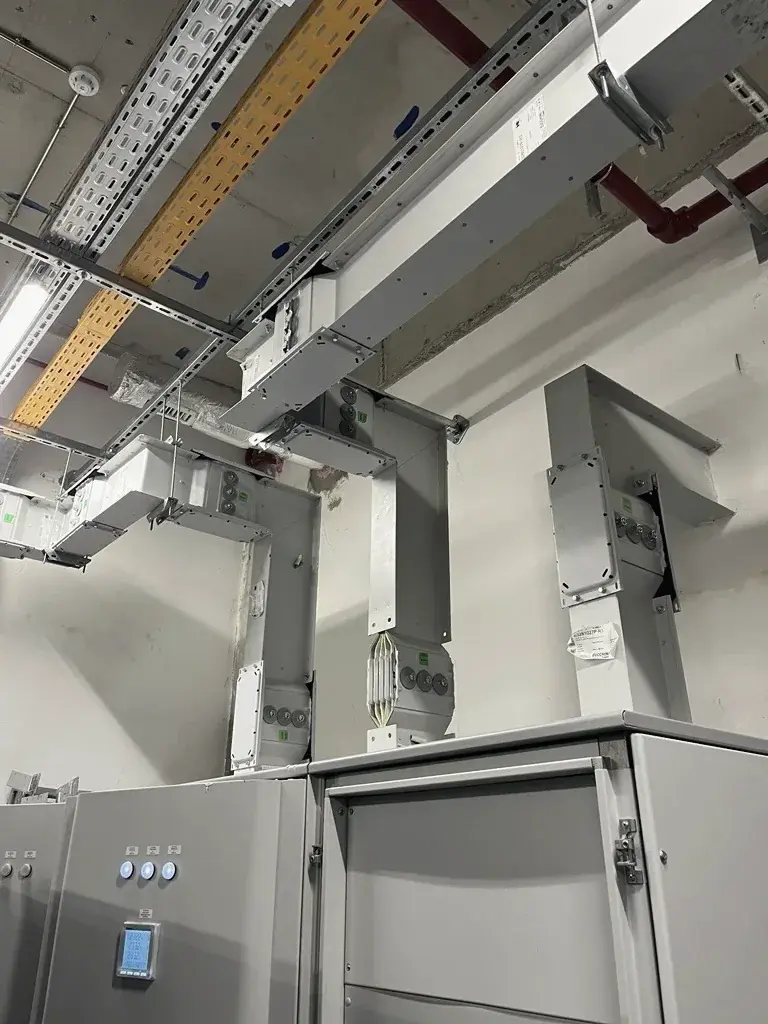 Busbar trunking rising from low-voltage panels to the ceiling of an electrical room