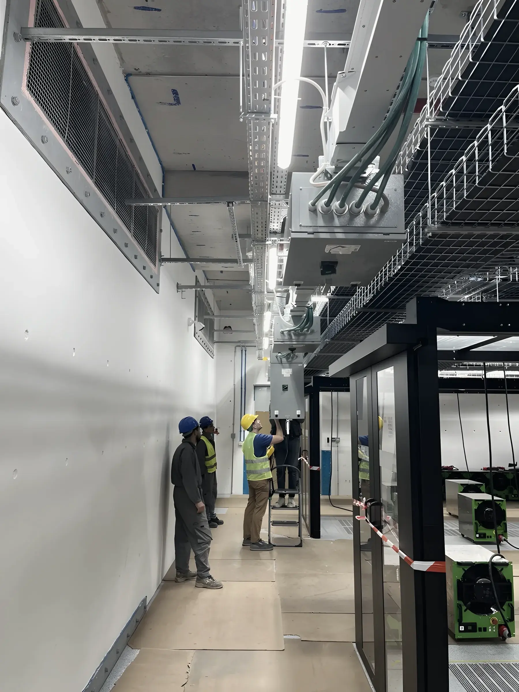 Three technicians in a service corridor during a construction walkdown